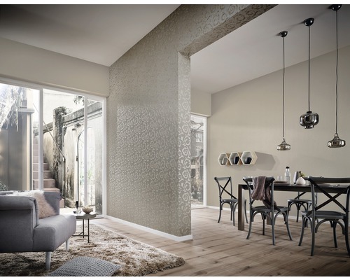 Vardagsrum med tapet, matbord och stolar samt en sittgrupp med fåtölj