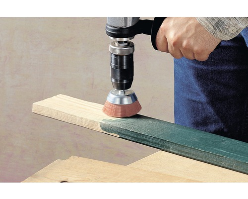 En borr med borstfäste slipar en träplanka.