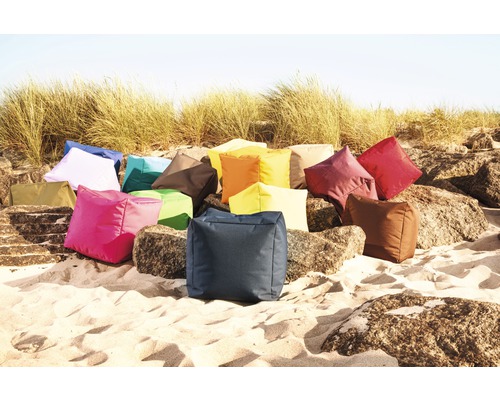 En samling fyrkantiga sittdynor i olika färger på sand och stenar.