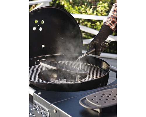 En person använder en grilltång på en kolgrill.