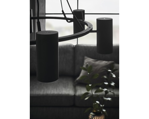 Interiörbild med en rund hänglampa och cylindriska lampskärmar ovanför en soffa