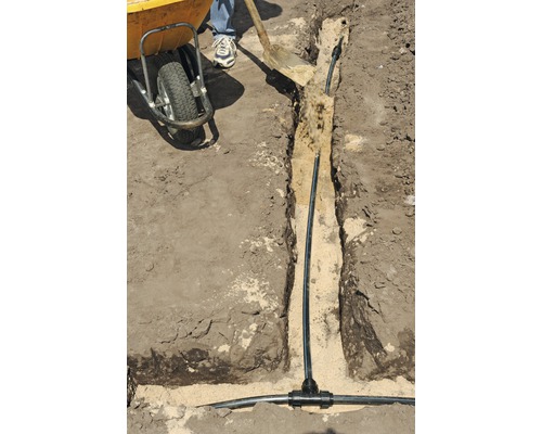 Bevattningssysteminstallation i trädgården med rör och spade