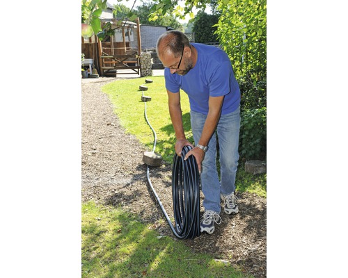 Man lägger ut bevattningsslang i trädgården