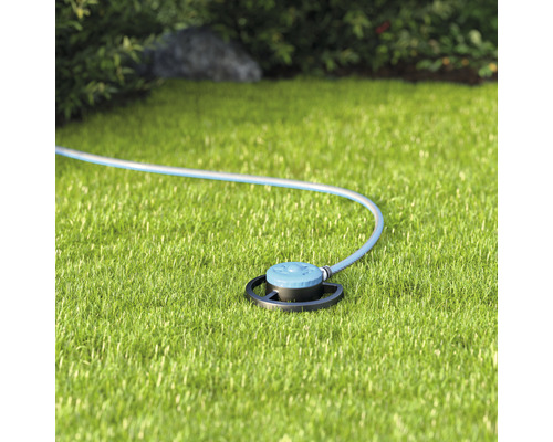 Grässpridare med slang på gräsmatta