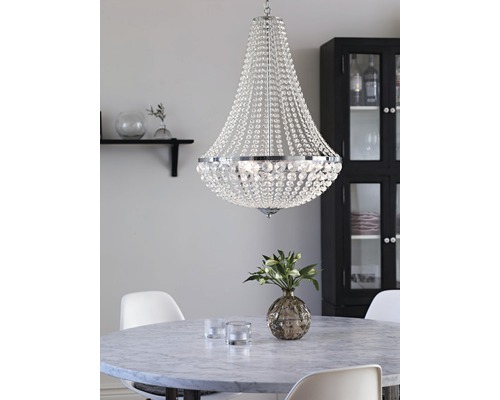 Kristallkrona ovanför ett matbord i ett ljust rum.