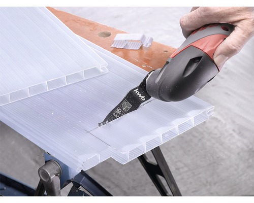 En person skär en kanalplastskiva med ett multiverktyg.