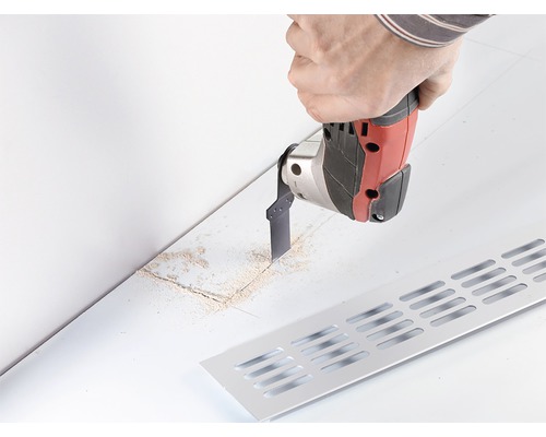 Scen med hantverkare som skär ett spår med ett multifunktionellt verktyg för ett ventilationsgaller