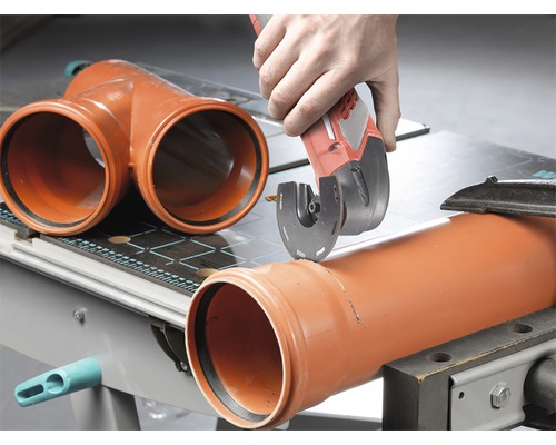 En man skär ett plaströr med ett multiverktyg på en arbetsbänk.