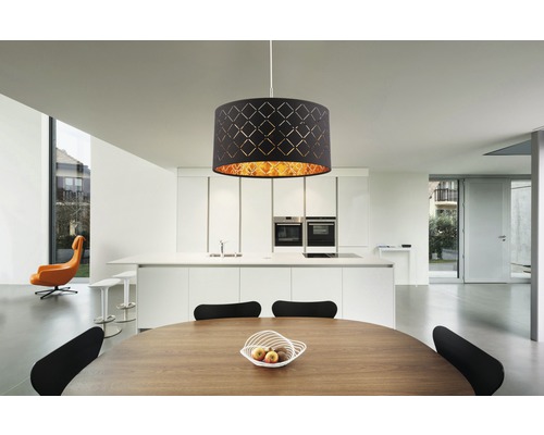 Pendellampa med mönstrad lampskärm över matbord i modern köksmiljö.