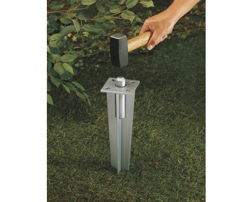 Metallstolpfäste slås ner i marken med en hammare.