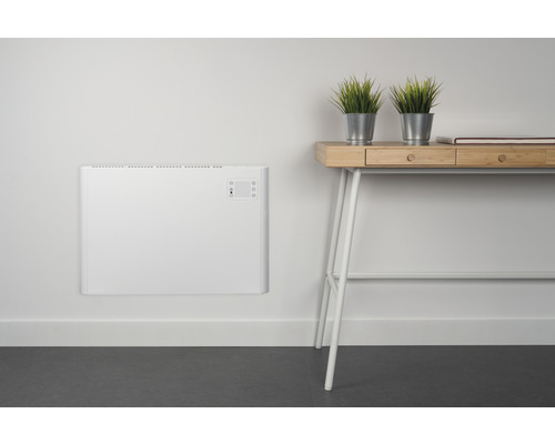 Väggmonterad radiator bredvid ett skrivbord med dekorativa växter.