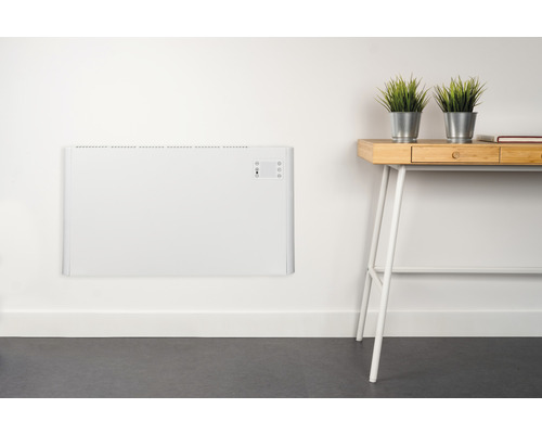 Väggmonterad, vit radiator bredvid ett skrivbord med växter