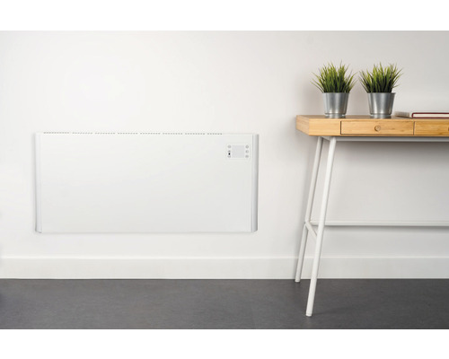 Väggmonterad konvektorvärmare i rum med skrivbord och dekoration