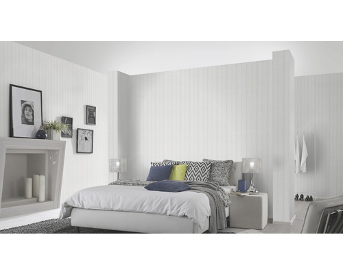 Ljust sovrum med säng, sängbord, dekoration och randig tapet