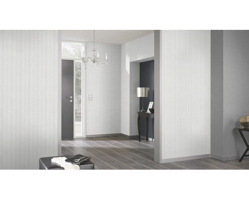 Ljus entré med randig tapet, ljuskrona och mörkt trägolv.