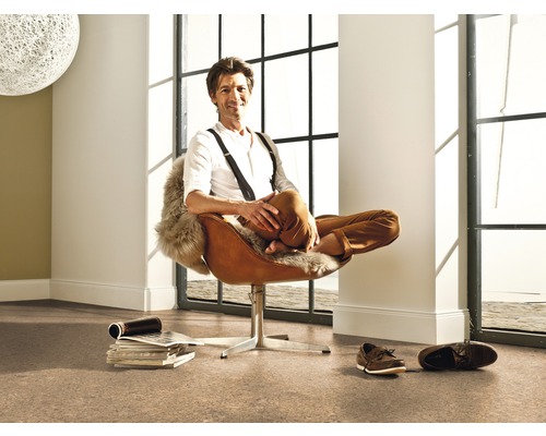 Ljust rum med korkgolv och man i brun fåtölj