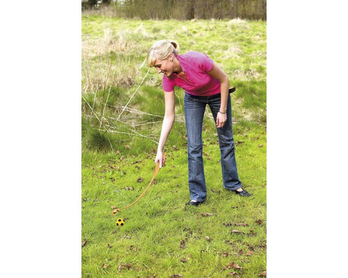 Kvinna använder bollslunga på en gräsmatta för att kasta en boll