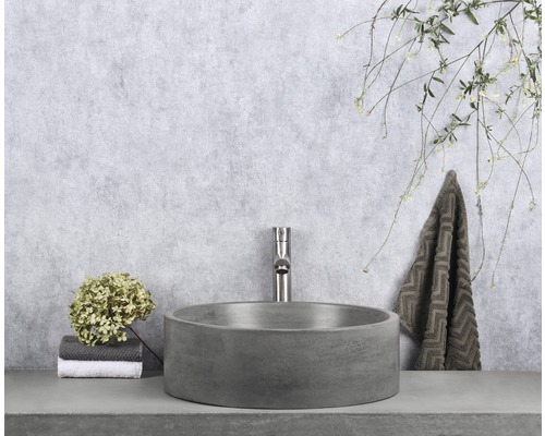 Badrumsscen med runt tvättställsskål, armatur och handduk