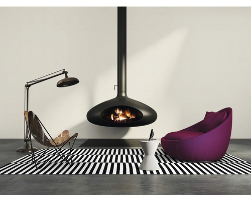 Vardagsrum med hängande eldstad, fåtölj och golvlampa på en svartvit randig matta