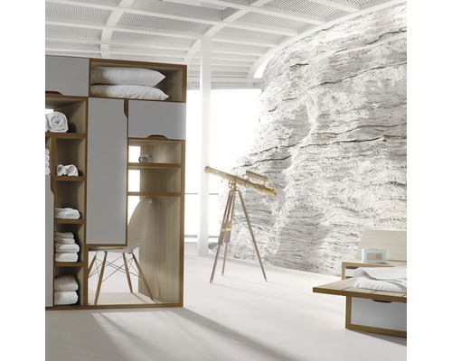 Ljust sovrum med garderob, fåtölj, teleskop och stenväggsdekoration