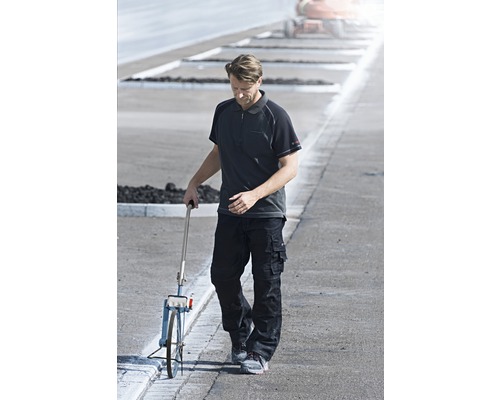 Man med mätinstrument på väg i arbetskläder