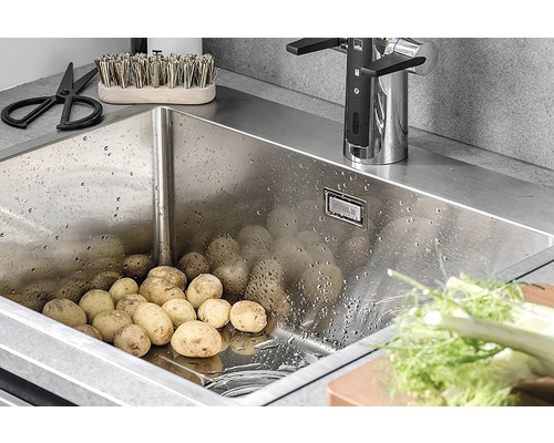 Rostfri diskho fylld med potatis, armatur och köksredskap.