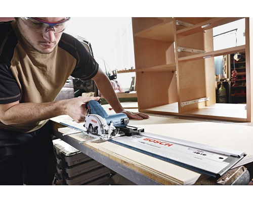 En man med skyddsglasögon skär trä med en handsåg och styrskena från Bosch.