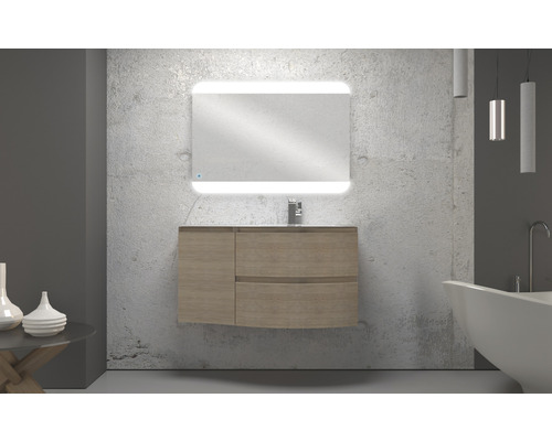 Badrum med tvättställsskåp, tvättställ, spegel med belysning och badkar.