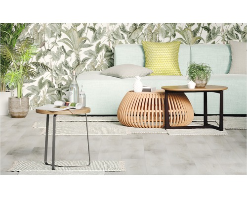 Vardagsrum med soffa, soffbord och växter framför en mönstrad tapet