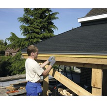 En man mäter en träkonstruktion med ett måttband.