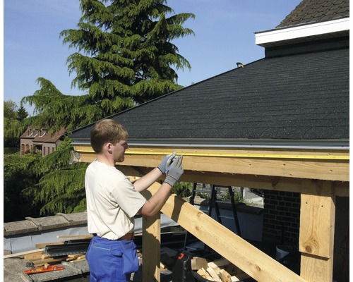 En man mäter en träkonstruktion med ett måttband.