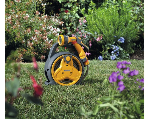 Trädgårdsslangvinda med slang och sprutpistol i trädgården