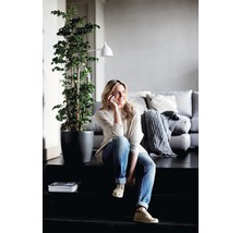 Ljust, vänligt vardagsrum med en kvinna som sitter på en trappa, en krukväxt och en soffa