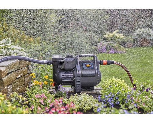 Trädgårdspump i drift med bevattning i trädgården.