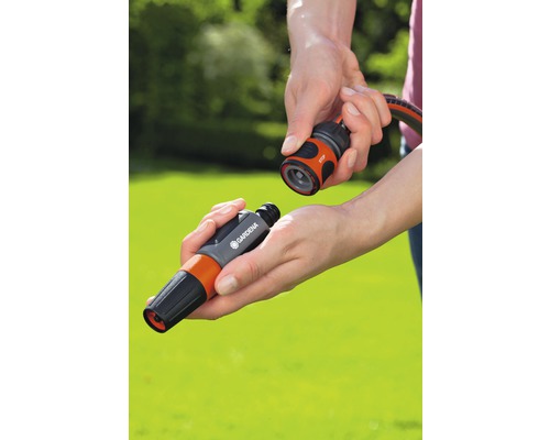 En person ansluter ett sprutmunstycke till en slangkoppling från Gardena.