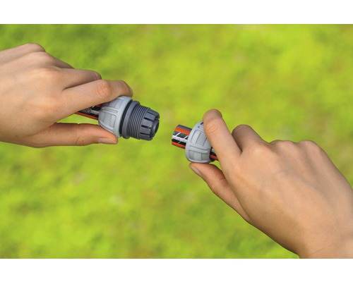 Två händer ansluter en slangkoppling till en trädgårdsslang.