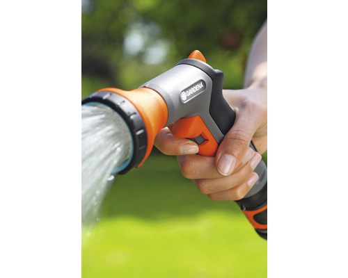 En hand håller en trädgårdsdusch från Gardena som vatten strömmar ur.