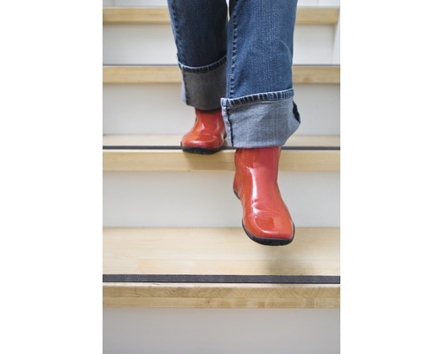 Person i stövlar går ner för trappor med halkskyddsremsor