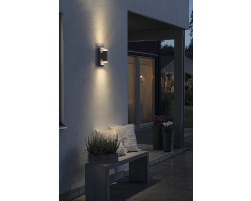 Uteplats med vägglampa, bänk och växter