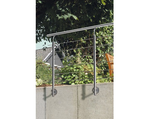 Rostfritt stålräcke framför en trädgårdsmur