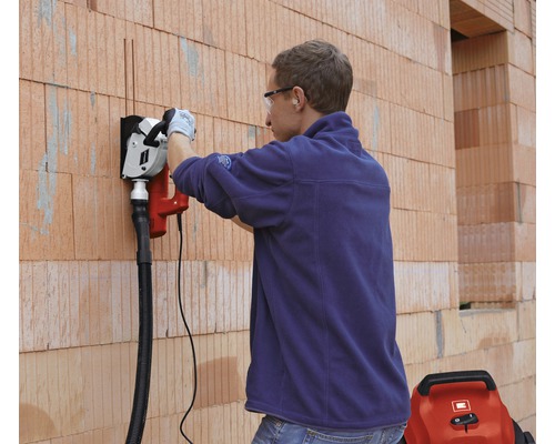 Man arbetar med en väggspårsfräs på en tegelvägg.
