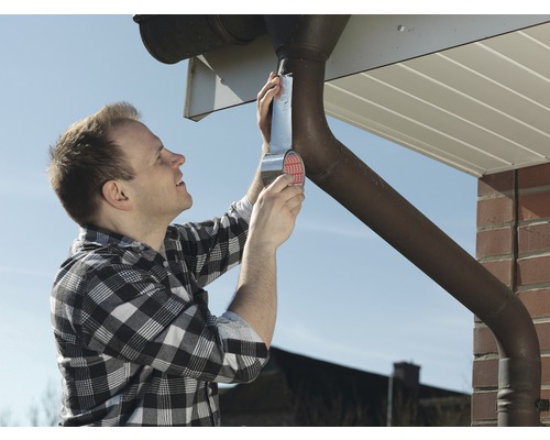 Man reparerar en takränna med tätningsband.