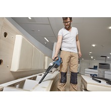 Man suger spån från en möbel med en batteridriven dammsugare.