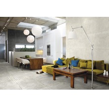 Ljust vardagsrum med golvplattor, soffa, bord och belysning