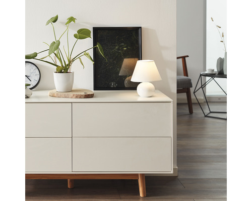 Sidobord i vardagsrum med bordslampa, krukväxt och tavla