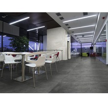 Interiör med sittplatser, bord och storformatiga golvplattor för en modern atmosfär.