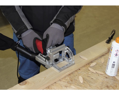 Hantverkare använder en lamellfräs på en träplanka, tillsammans med träkontakter och lim.