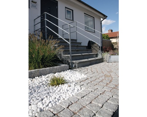 Exteriör av ett hus med stentrappa, räcke, dekorativt grus och gatsten