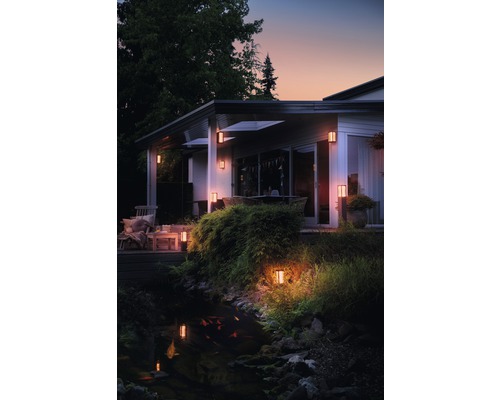 Upplyst hus med trädgård, damm och utomhusbelysning
