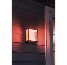 Belyst, kubformad utomhusvägglampa på en husvägg